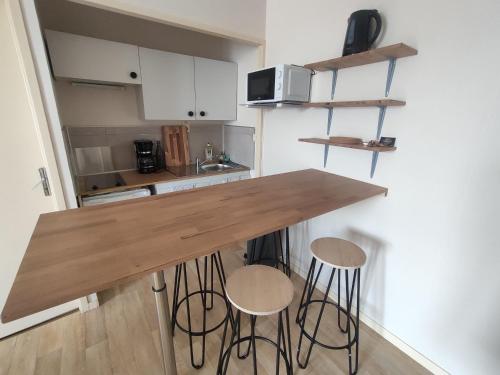 une cuisine avec un comptoir en bois et deux tabourets dans l'établissement Charmant appartement - 5 mn Zoo de Beauval 4p, à Saint-Aignan