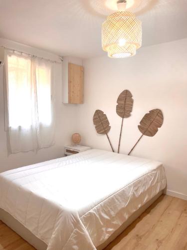 une chambre avec un grand lit blanc avec un lustre dans l'établissement Appartement 30m2 cosy avec terrasse, à Menton