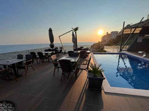 um restaurante com piscina e mesas e o oceano em Apart Lux Beciragic em Dobra Voda