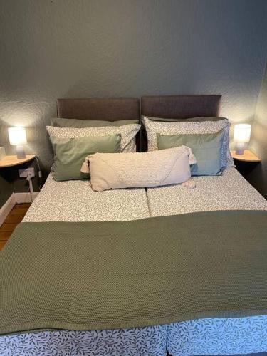 a bed with four pillows on it with two lamps at Cosy 2 bed flat in Crickhowell in Crickhowell