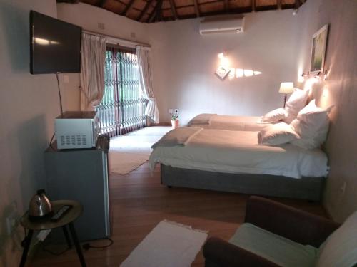 a bedroom with two beds and a television and a couch at Ekuphumleni Holistic Healing Center in Johannesburg