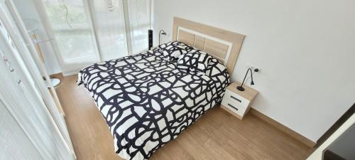 een slaapkamer met een bed met een zwart-wit dekbed bij STAY HOME GETXO Metro and Beach in Getxo