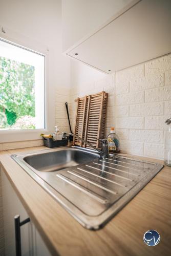 un comptoir de cuisine avec un évier et une fenêtre dans l'établissement Mazet au calme -Piscine privée-Grand jardin arboré, à Saint-Quentin-la-Poterie