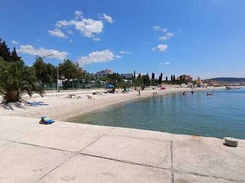 a beach with a bunch of people in the water at Apartman Čarija in Trogir