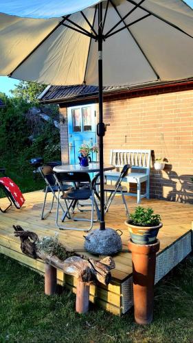 an umbrella on a wooden deck with a table and chairs at Lunden in Vittaryd