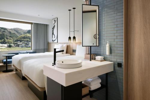 a bathroom with a sink and a bed with a mirror at Fairfield by Marriott Okayama Tsuyama in Tuyama