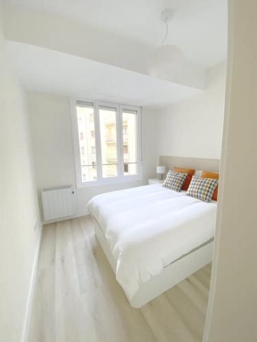 um quarto branco com uma cama grande e uma janela em ALBAOLA APARMENT em San Sebastián