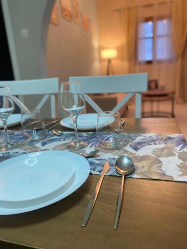 a wooden table with a white plate and glasses on it at Oxo Kamara Apartment in Karpathos Town