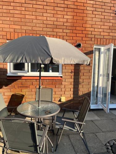 una mesa y sillas con sombrilla frente a un edificio de ladrillo en Canada House - Sleeps 6 -3 King or 6 Single Ideal for contractors, en Warrington