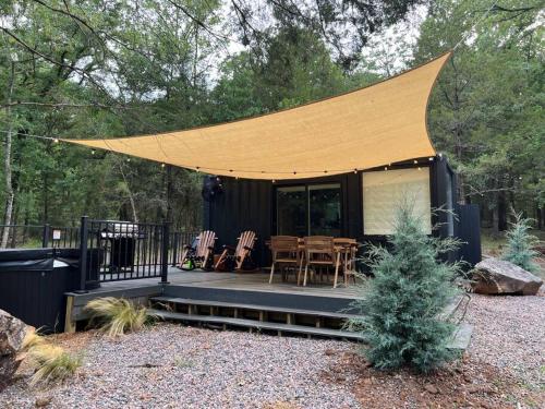 une maison noire avec une grande tente sur un patio dans l'établissement HiddenAcres Cabin - woodsy private couples retreat, à Eustace