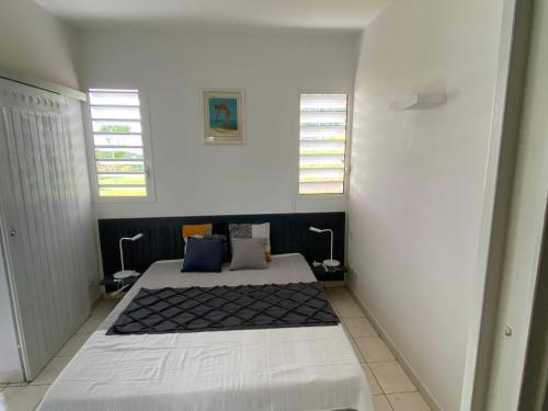 um quarto branco com uma cama e 2 janelas em Le 63* em La Trinité