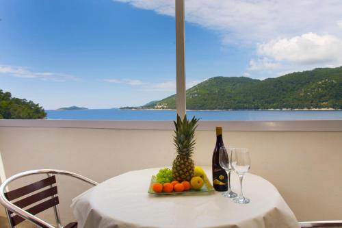 a table with a plate of fruit and a bottle of wine at Apartments Marija in Brna