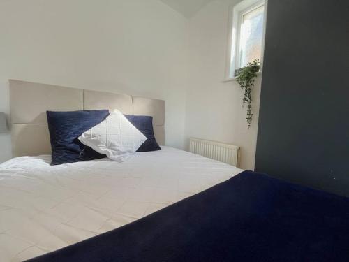 um quarto com uma grande cama branca com almofadas azuis em Woodside Road, Southbourne em Bournemouth