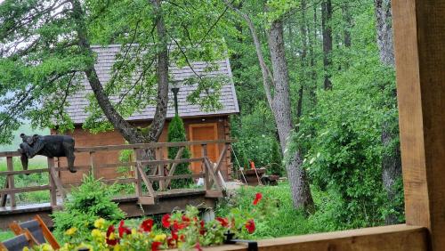 una cabaña en el bosque con un oso negro de pie en una valla en Vodenica Vrelo Chalets, en Vrelo Koreničko