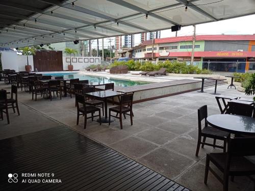 um pátio com mesas e cadeiras e uma piscina em Loft Encantador, a beira mar! em Salvador