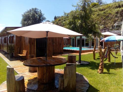 uma mesa com um guarda-chuva ao lado de uma piscina em Casa do Outeiro em Arcos de Valdevez