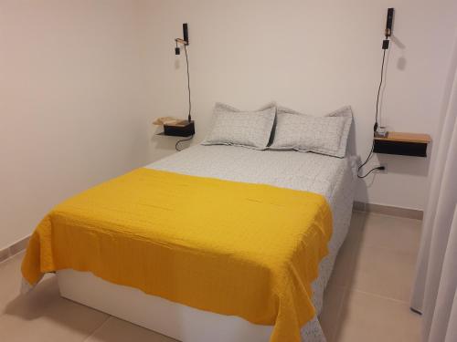 1 dormitorio con 1 cama con manta amarilla en Casa a estrenar! A 5 minutos de la terminal de omnibus y muy cerca del centro! en El Calafate