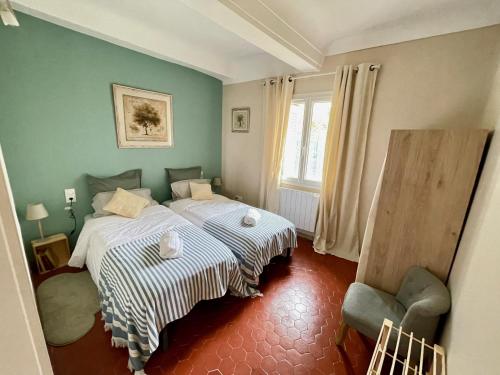 ein Schlafzimmer mit 2 Betten und einem Stuhl darin in der Unterkunft Détente parfumée, capitale du parfum in Grasse