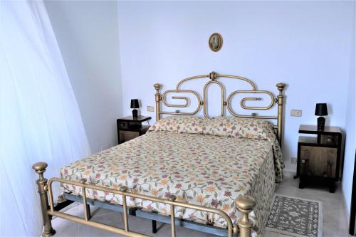 a bedroom with a metal bed with a floral bedspread at Dimora Calliope in Naso