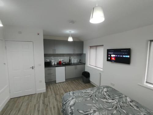 a white room with a bed and a kitchen at Charming Studio Flat with Parking in Enfield