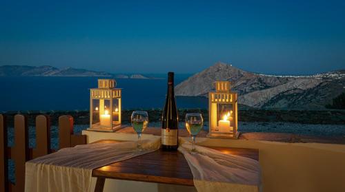 a bottle of wine and two glasses on a table with candles at Aegean Balcony Studio in Áno Meriá