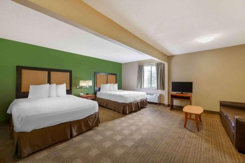 a hotel room with two beds and a flat screen tv at Extended Stay America Suites - Cincinnati - Blue Ash - Reagan Hwy in Blue Ash