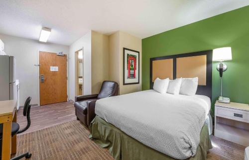 a hotel room with a large bed and a chair at Extended Stay America Suites - Cincinnati - Blue Ash - Kenwood Road in Blue Ash