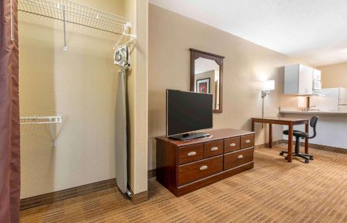 a hotel room with a television on a dresser with a desk at Extended Stay America Suites - Indianapolis - Airport in Indianapolis