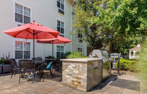 a patio with a grill and red umbrellas at Extended Stay America Suites - Chantilly - Dulles in Chantilly