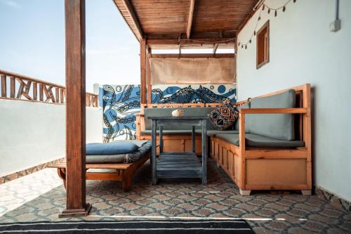 a porch with a bed and a table and a chair at Rafiki Hostels - Dahab in Dahab