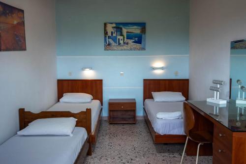 a room with two beds and a desk with a desk at Katerina Studios & Apartments in Sidari