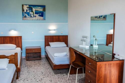 a room with two beds and a desk with a mirror at Katerina Studios & Apartments in Sidari