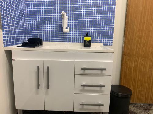 a bathroom with a sink and a blue tiled wall at Kitnet Penha CEFAN ADVEC in Rio de Janeiro