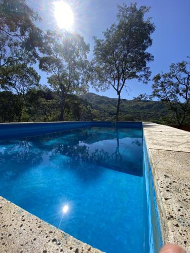 uma piscina com água azul e árvores ao fundo em Cabañas La Misión em Salta