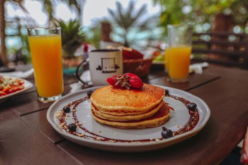 a plate of pancakes on a table with two glasses of orange juice at Aluxes Bacalar in Bacalar