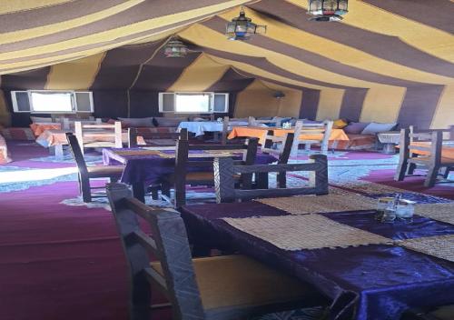 a dining room with tables and chairs in a tent at Luxury Desert Romantic Camp in Merzouga