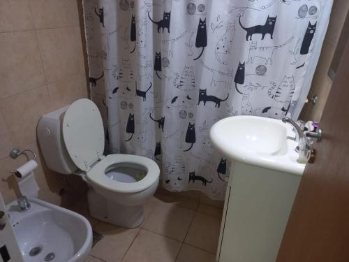 a bathroom with a toilet and a sink and a shower curtain at Depto Luminoso 1 Dormitorio para 2 con Patio in Rosario