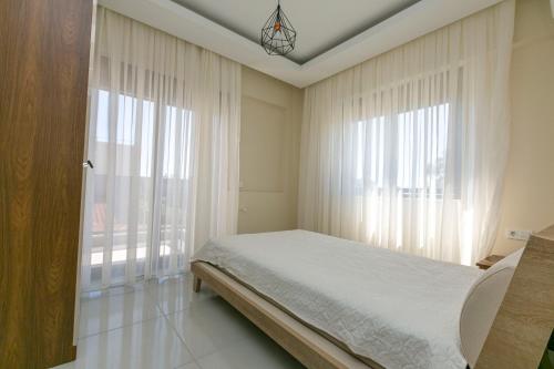 a bedroom with a bed and two large windows at Paradise Town Villa Lisa in Belek