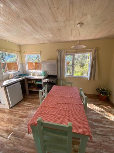 cocina con mesa roja y sillas en una habitación en Cabañas La Misión en Salta
