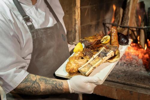 a man holding a plate of food on a grill at Los Ñires Ushuaia in Ushuaia
