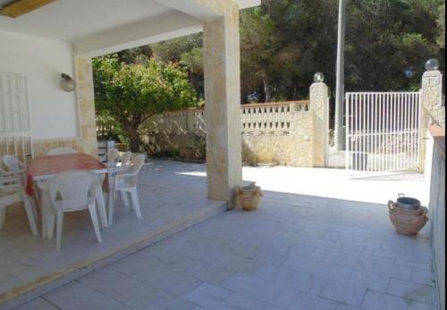 un patio con tavolo, sedie bianche e tavolo di Villa Papi a Marina di Lizzano