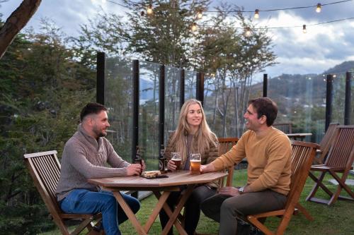 a group of three people sitting around a wooden table at Los Ñires Ushuaia in Ushuaia