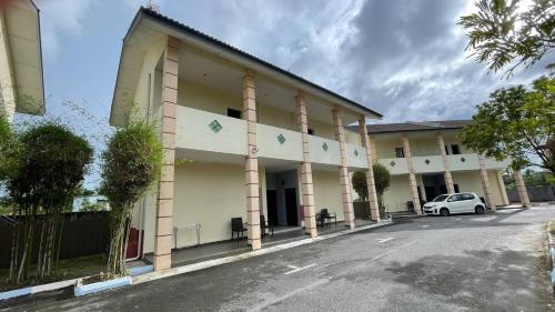 a white car parked in front of a building at Adina Drive-In Motel Cenang - Managed By Shell Out Resort in Pantai Cenang