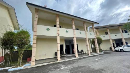 a building with columns and a car parked in front at Adina Drive-In Motel Cenang - Managed By Shell Out Resort in Pantai Cenang