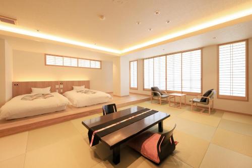 a bedroom with a bed and a desk and chairs at Yuyado Mikannoki in Atami
