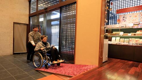 a man and a woman in a wheelchair in a store at Yuyado Mikannoki in Atami