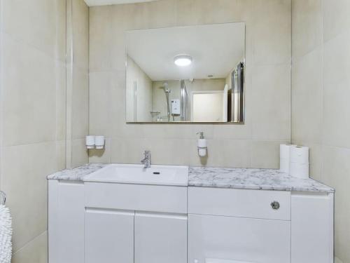 a white bathroom with a sink and a mirror at Luxury Accommodation with TVs in each Room in Macclesfield