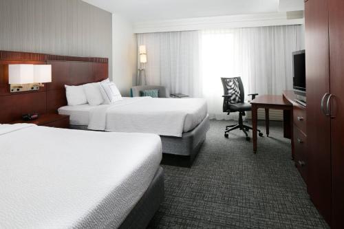 a hotel room with two beds and a desk at Courtyard by Marriott Omaha Aksarben Village in Omaha