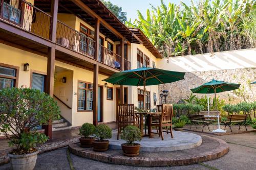 a patio with a table and chairs and umbrellas at Pousada Rotunda in São João del Rei