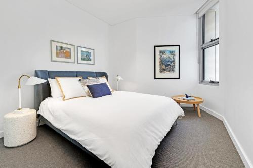 ein weißes Schlafzimmer mit einem großen weißen Bett und zwei Fenstern in der Unterkunft The View by Experience Jervis Bay in Huskisson